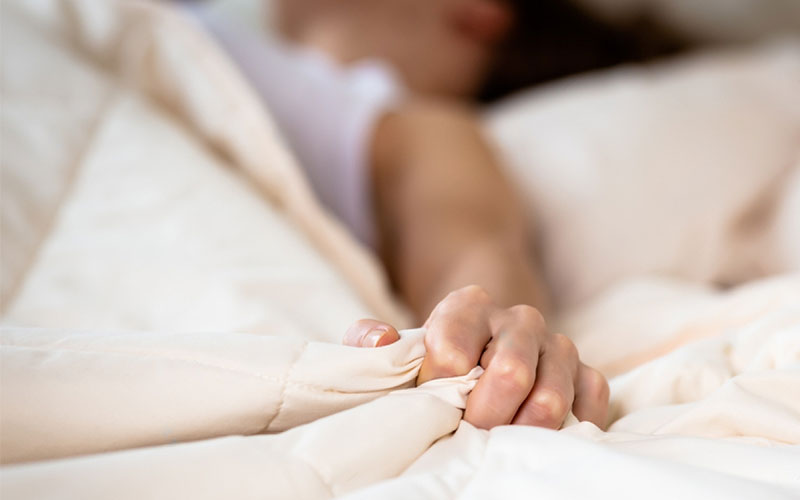 یک خانم در حال فشردن انگشتانش روی تخت