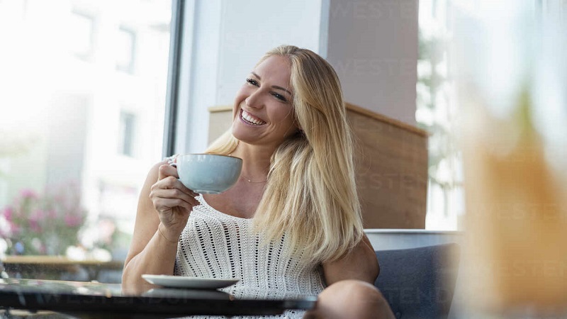 یک خانم خندان در حال نوشیدن قهوه