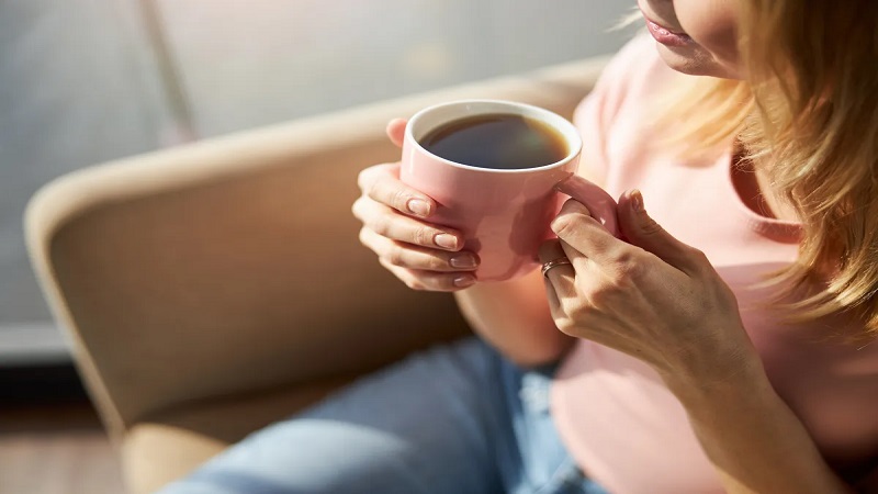 یک خانم که لیوان قهوه در دست دارد